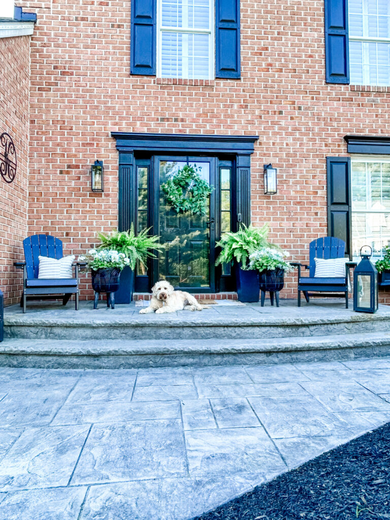 Welcoming Front Porch a welcoming front porch setup featuring a brick home exterior, black seating, and green plants
