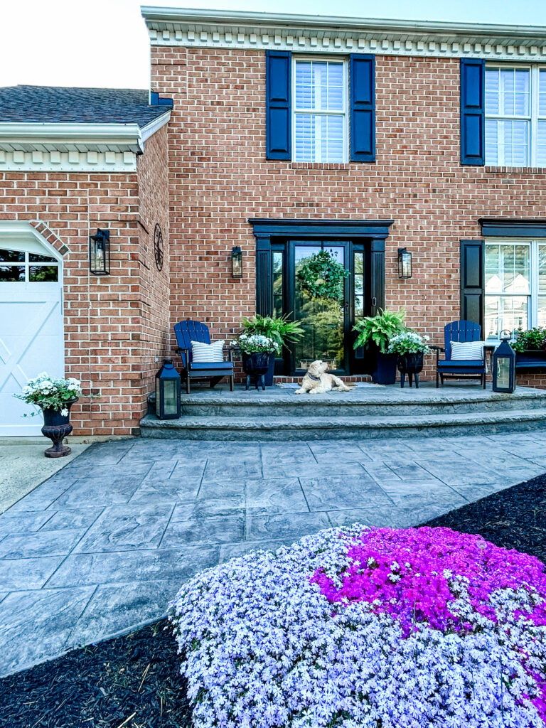 Welcoming Front Porch brick home decorated with black planters of varying heights and black outdoor furniture