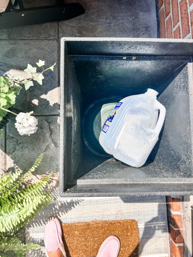 Welcoming Front Porch an empty water jug on top of the upside down planter
