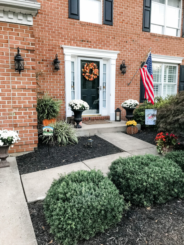 Welcoming Front Porch a festive fall front porch makeover featuring a seasonal wreath, layered planters, and pumpkins