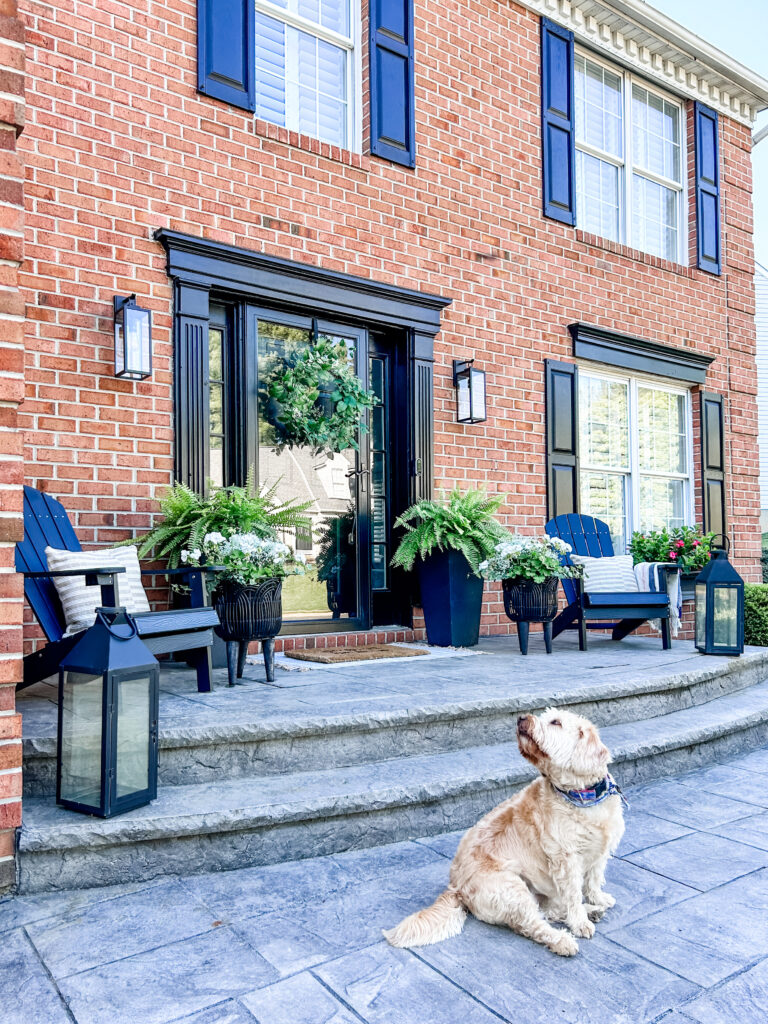 Welcoming Front Porch a black door flanked by black planters on a brick porch